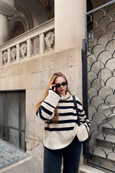 a lady in a striped mock neck sweater and a pair of black pants